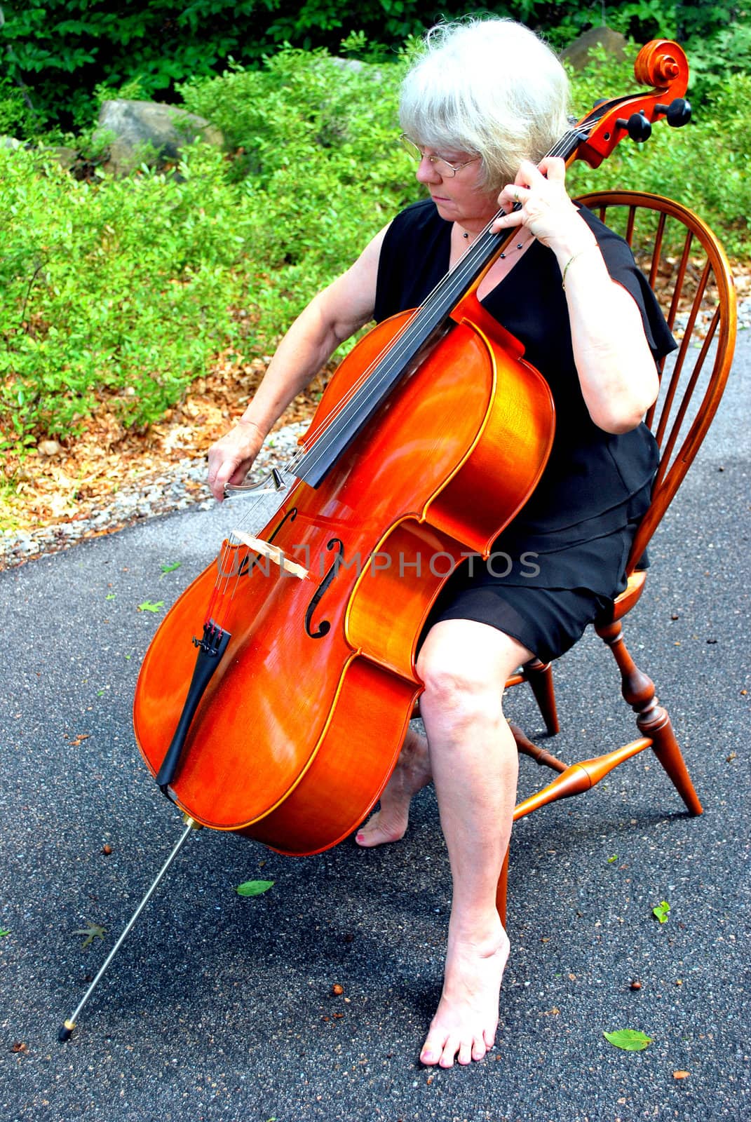 Female cellist posing with her cello outside.