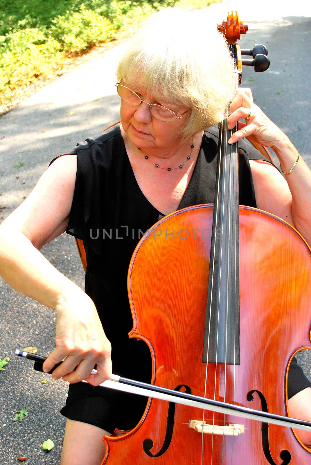 Female cellist posing with her cello outside.