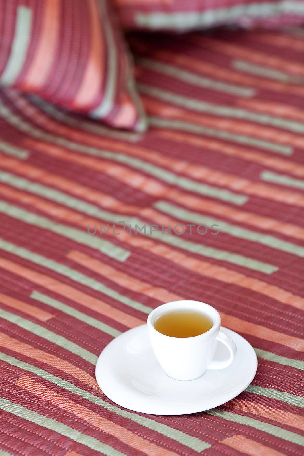 bed with two pillows, a cup of tea on the blanket