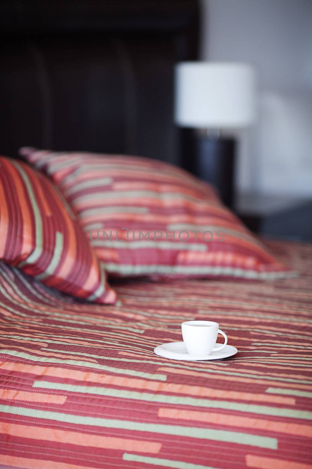 bed with a pillow, a cup of tea on the bedside table and lamp by jannyjus