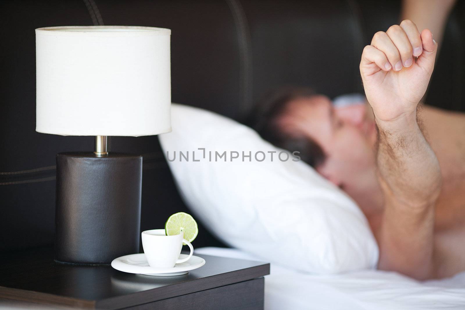 waking up man and a cup of tea on the bedside table and lamp by jannyjus