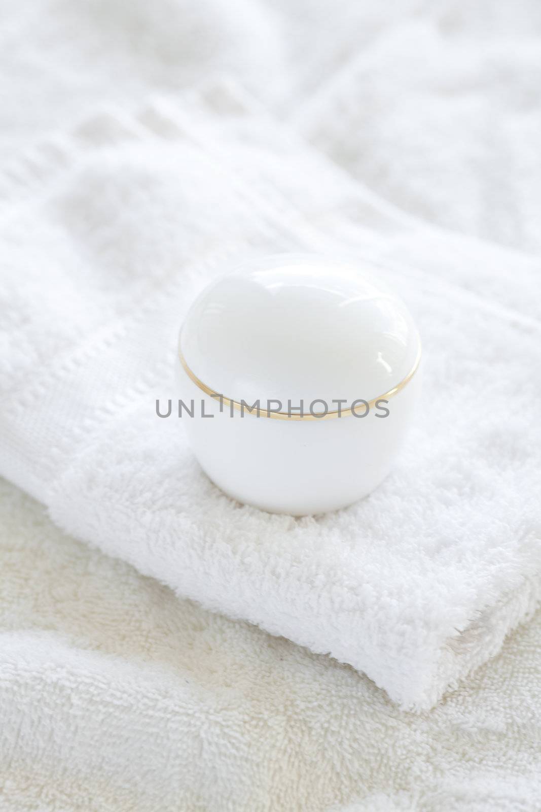 cosmetic containers lying on white towel by jannyjus