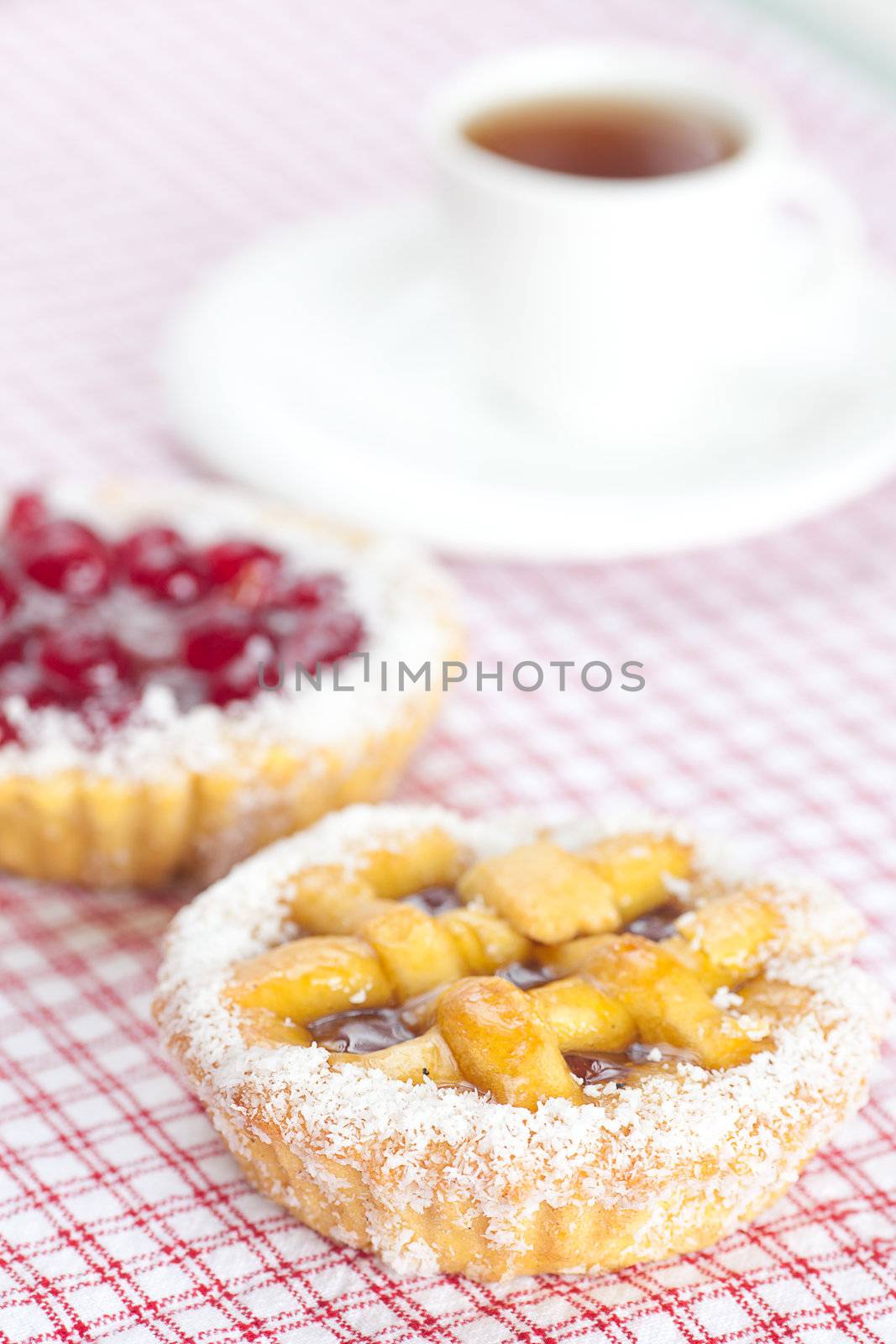 beautiful cake with berries and tea on plaid fabric by jannyjus