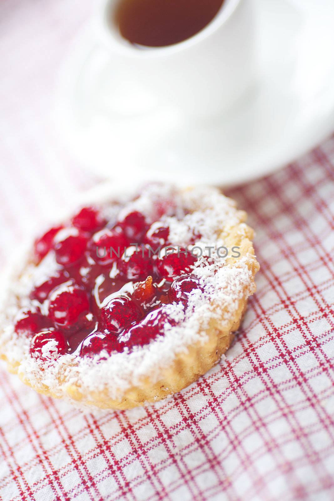 beautiful cake with berries and tea on plaid fabric