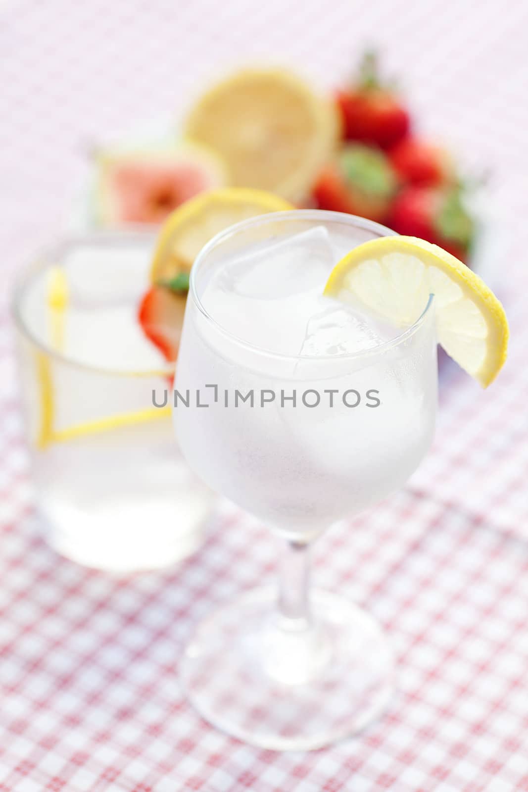 cocktail with ice,lemon, fig and strawberries on a plate by jannyjus