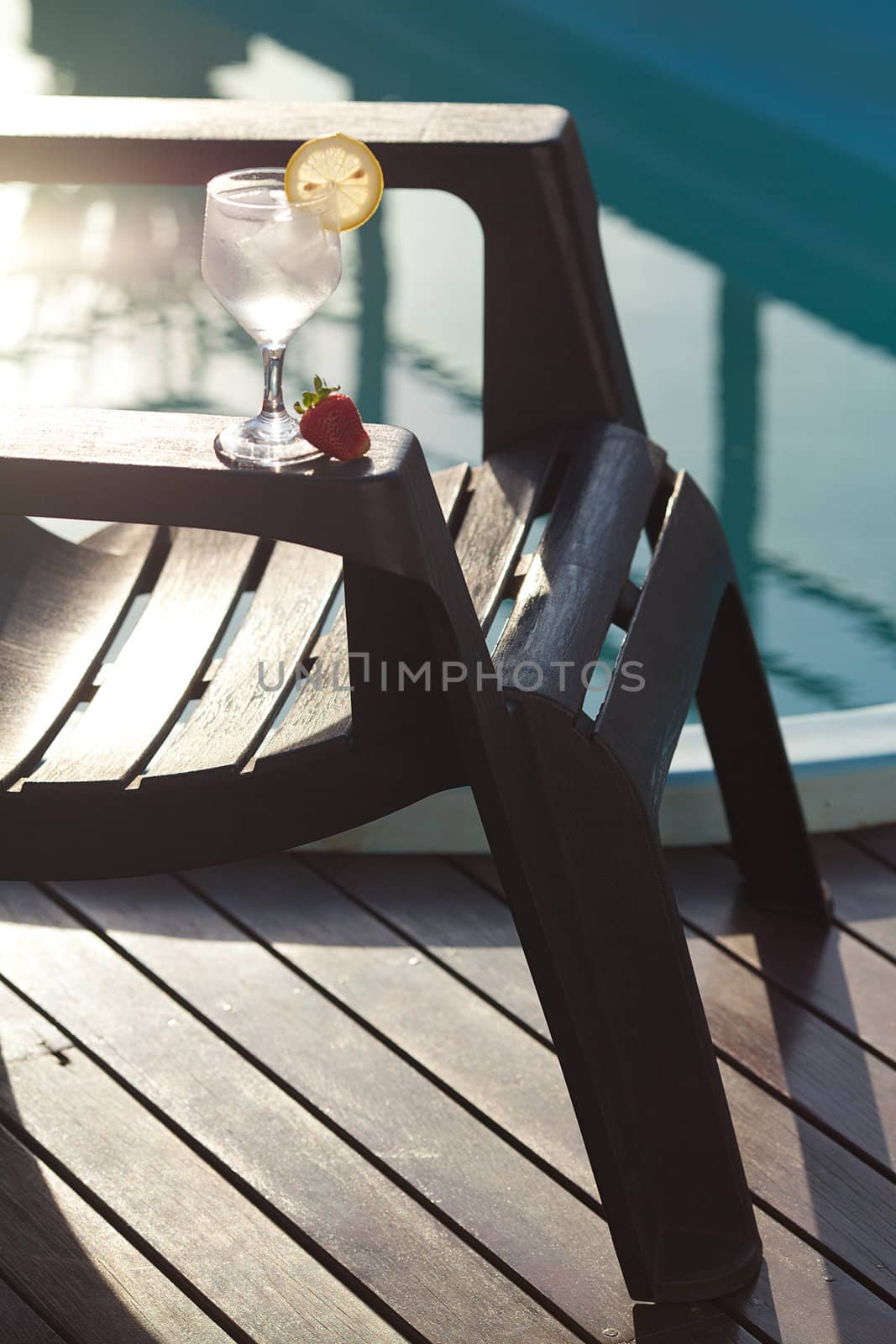 Swimming pool, lounge, a wine glass with ice, lemon and strawberry