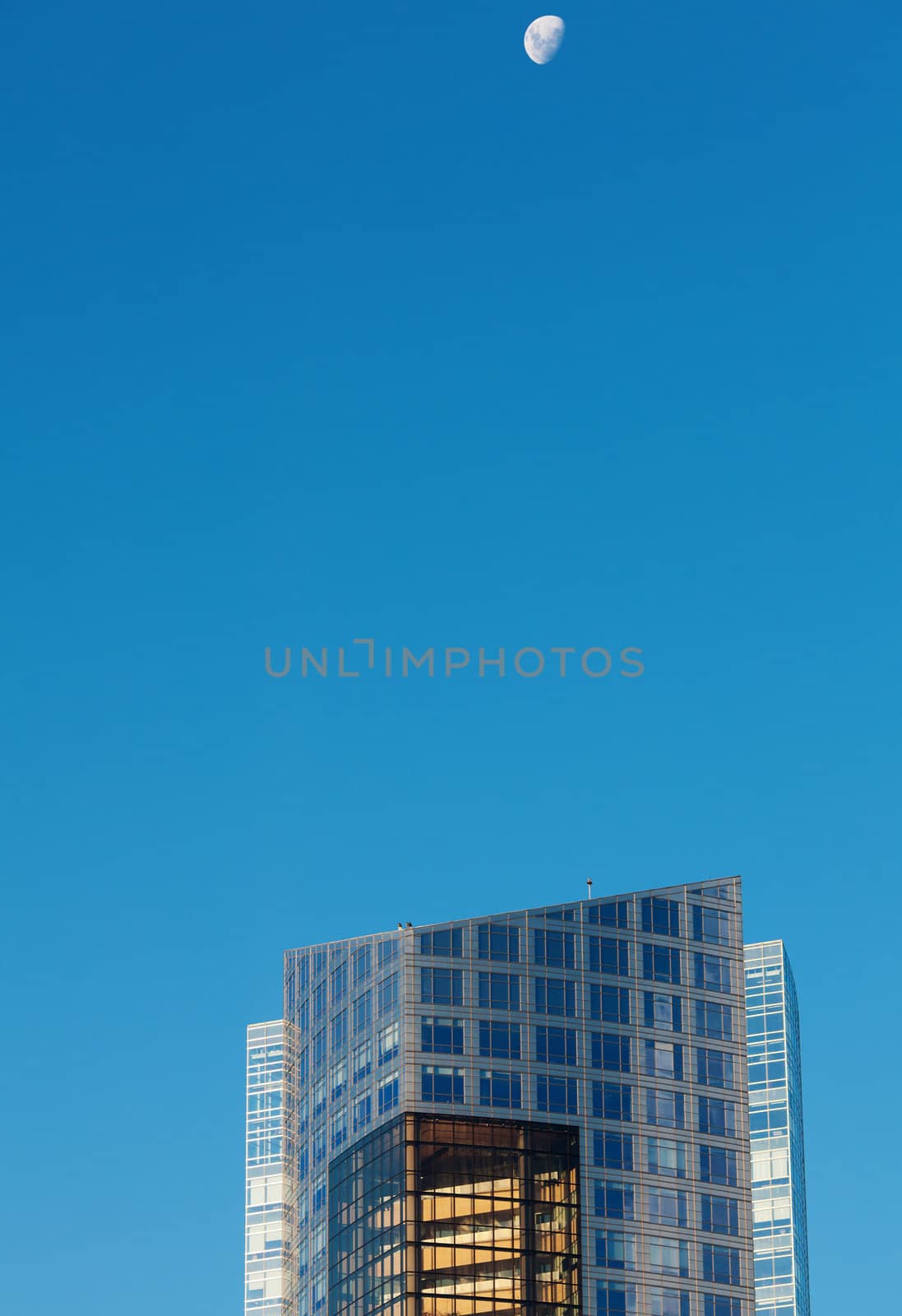 Beautiful modern office buildings and the moon against the blue sky