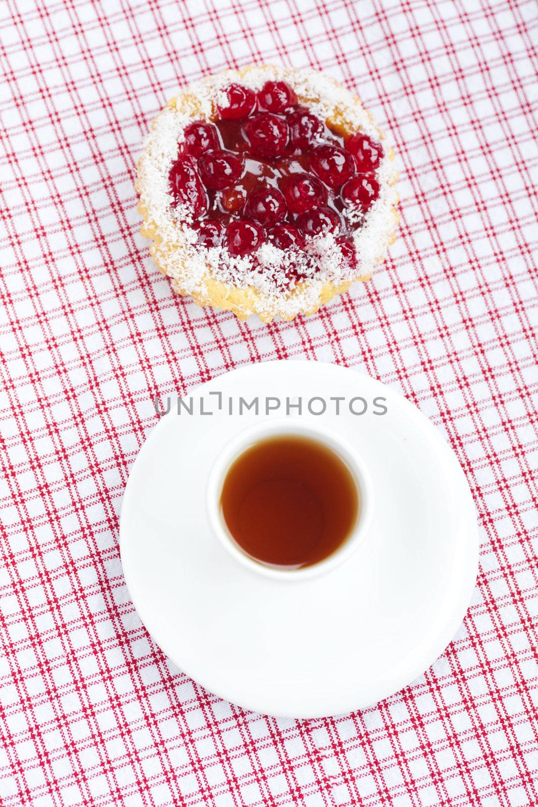 beautiful cake with berries and tea on plaid fabric by jannyjus