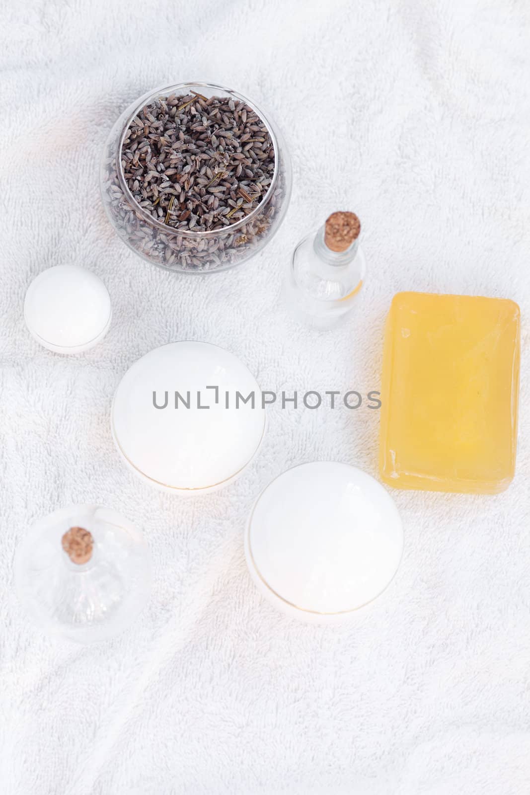 cosmetic containers, bottles, soap and lavender on a white towel