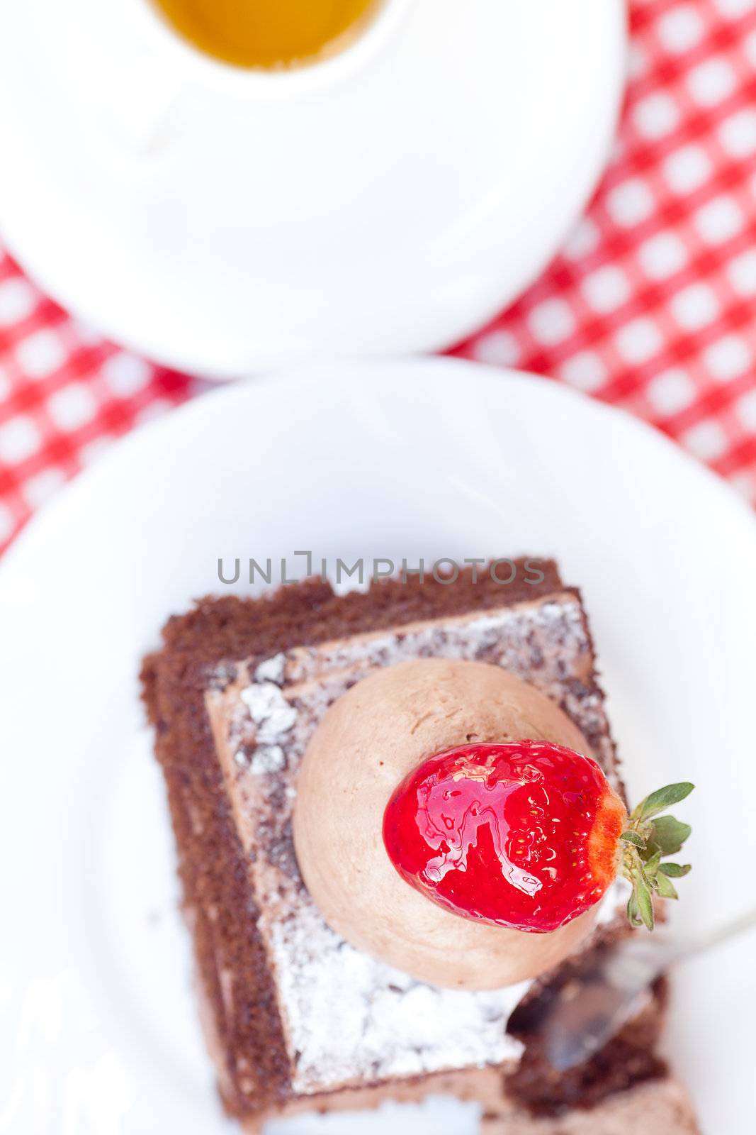 beautiful cake with strawberry and tea on plaid fabric