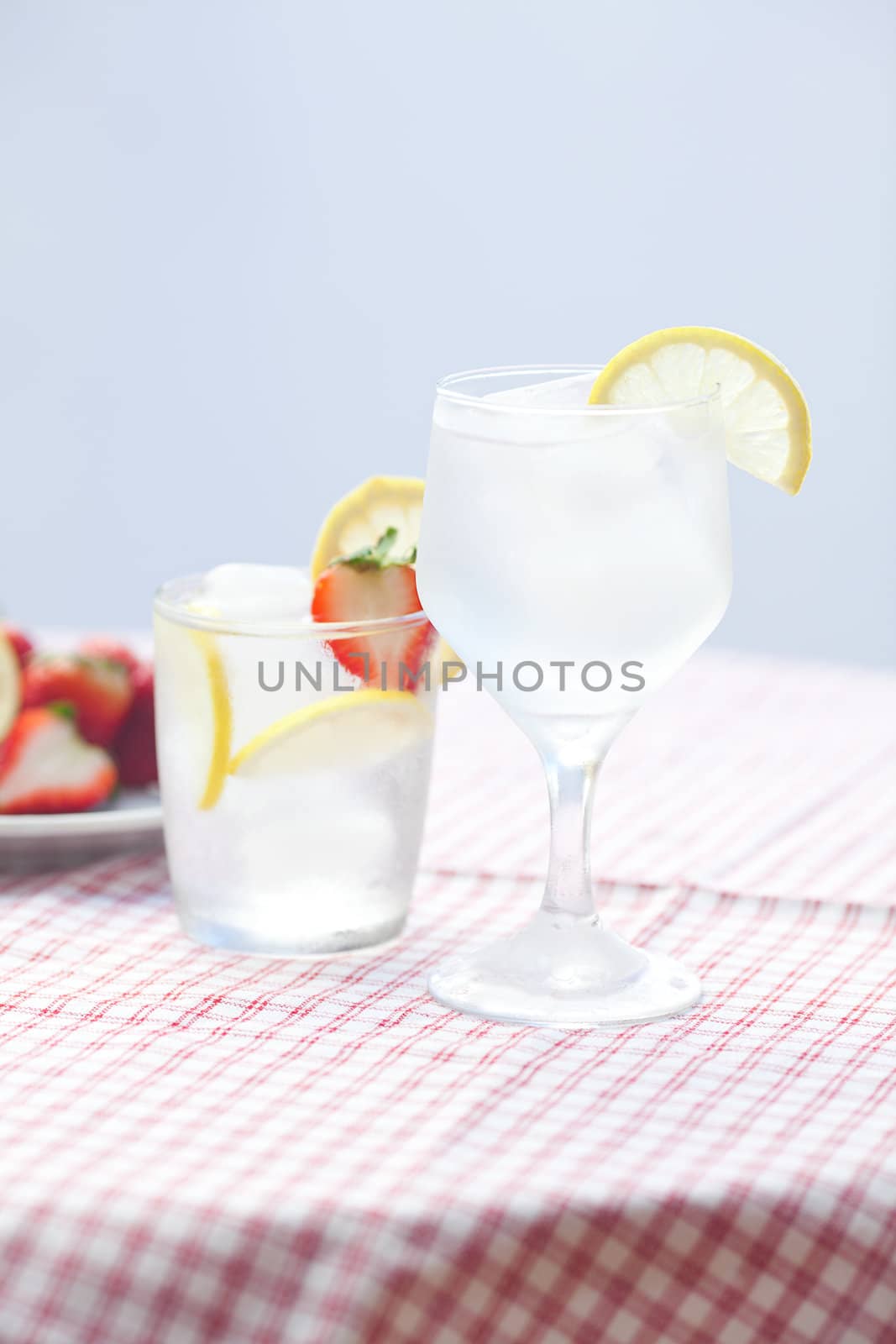 cocktail with ice,lemon and strawberries on a plate by jannyjus