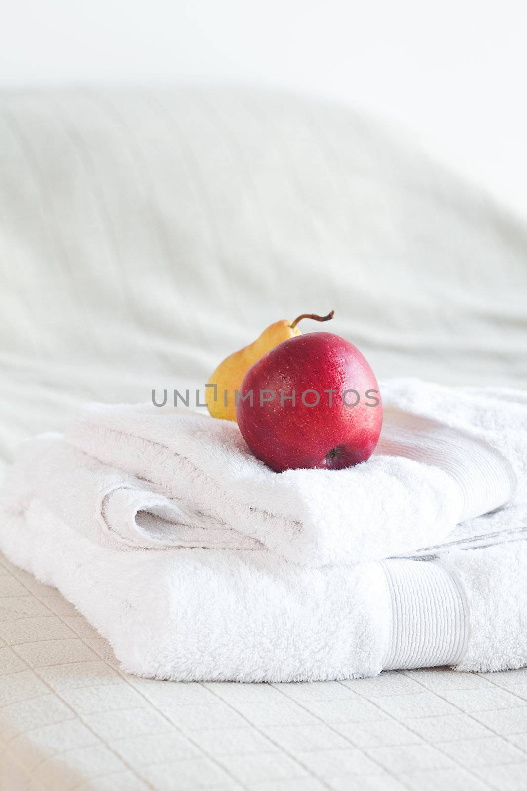 apple and pear on towels on the bed 