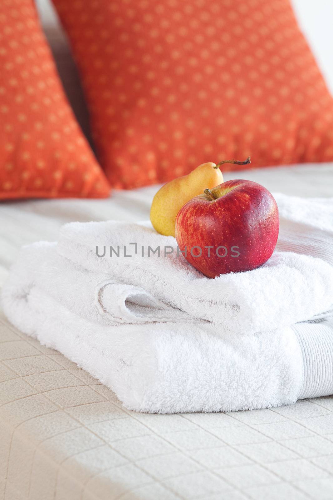 apple and pear on towels on the bed with two pillows