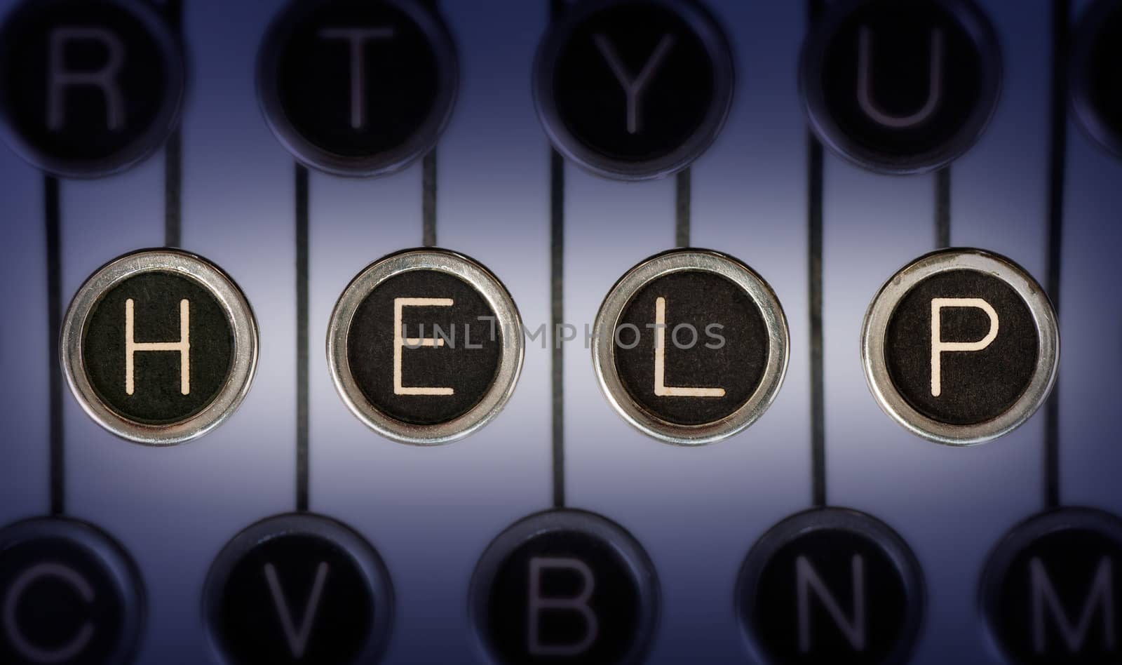 Close up of old typewriter keyboard with scratched chrome keys that spell out the word "HELP". Lighting and focus are centered on "HELP". 