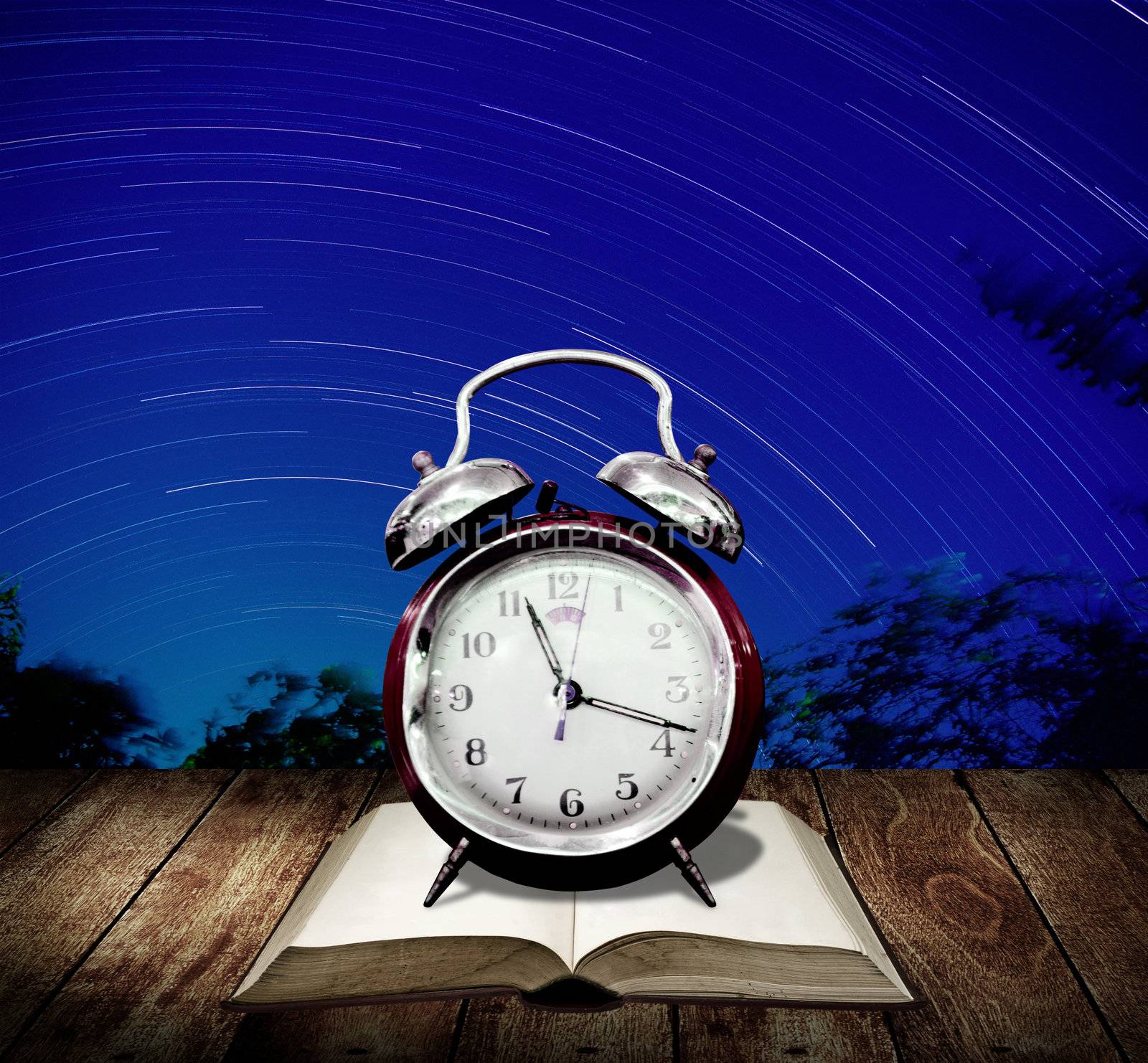 Alarm clock with star trails background. Read for examination