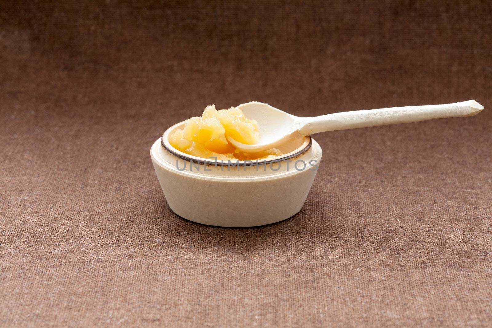 Pot of honey and wooden dipper on a cloth background