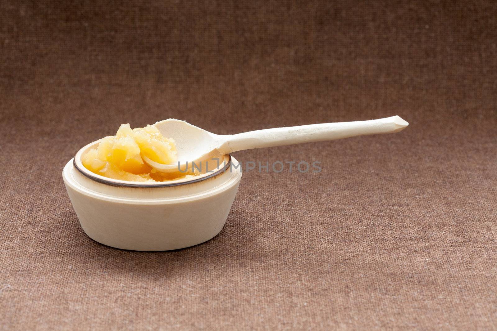 Pot of honey and wooden spoon on a burlap background