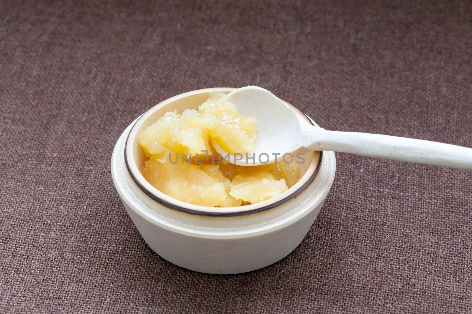 Pot of honey and wooden spoon on a cloth background