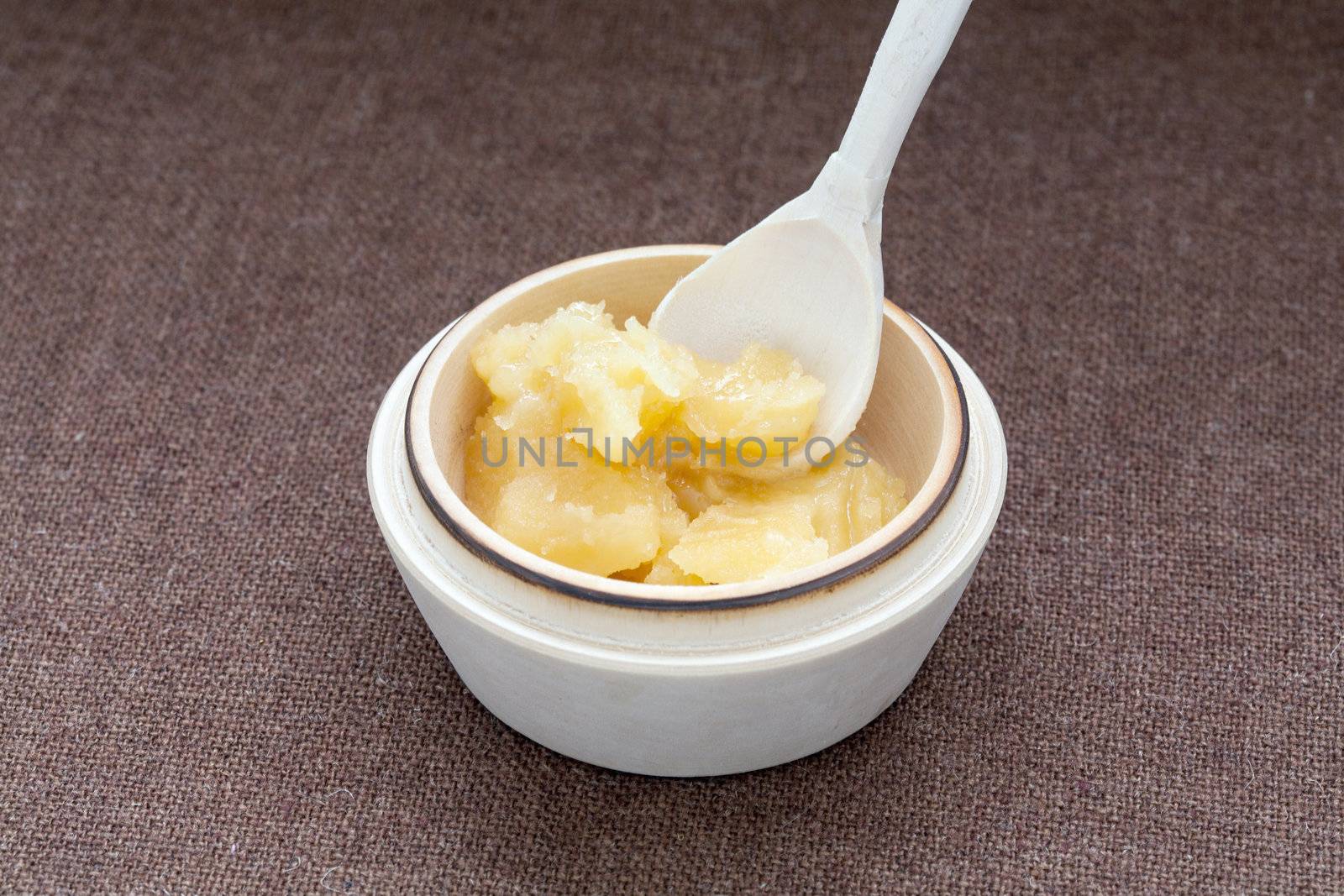 Pot of honey and wooden dipper on a cloth background