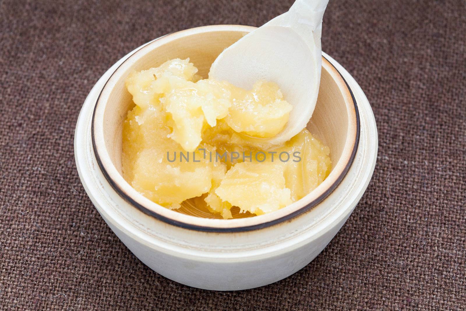 Pot of honey and wooden spoon on a bagging background