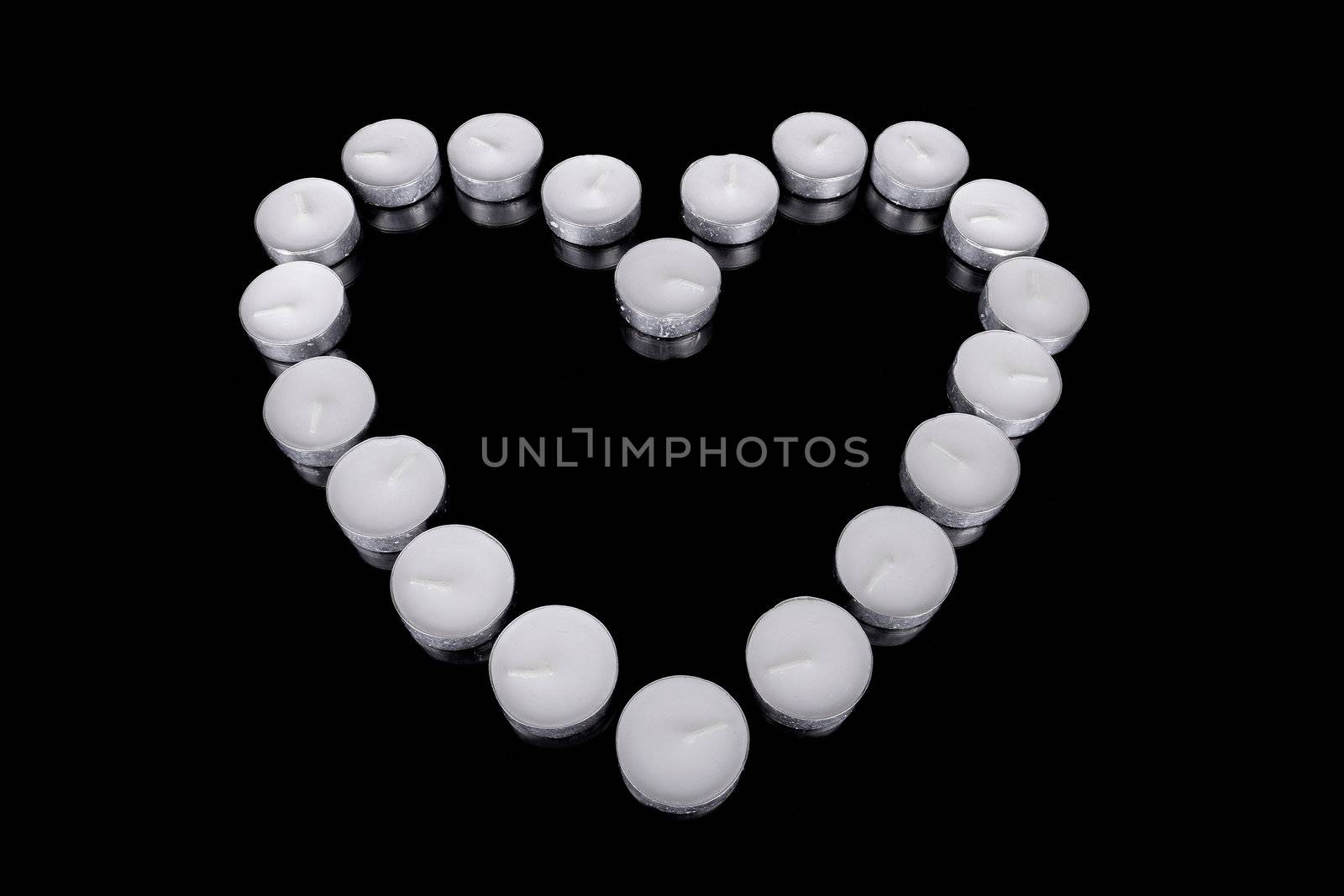 Group of white candles forming a heart  on black isolated background. Concept for St. Valentine by HERRAEZ