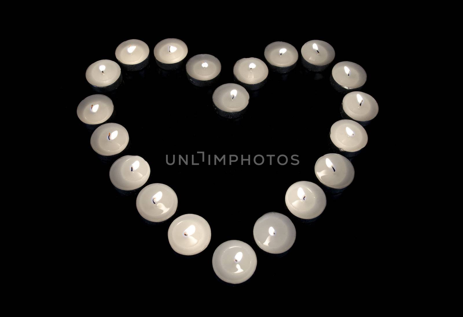 Group of burning candles forming a heart  on black isolated background. Concept for St. Valentine by HERRAEZ
