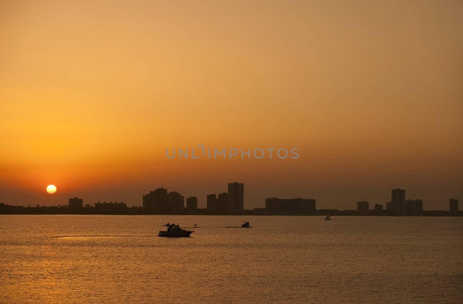 Beautiful sunset above the sea with boats and people practising aquatic sports
