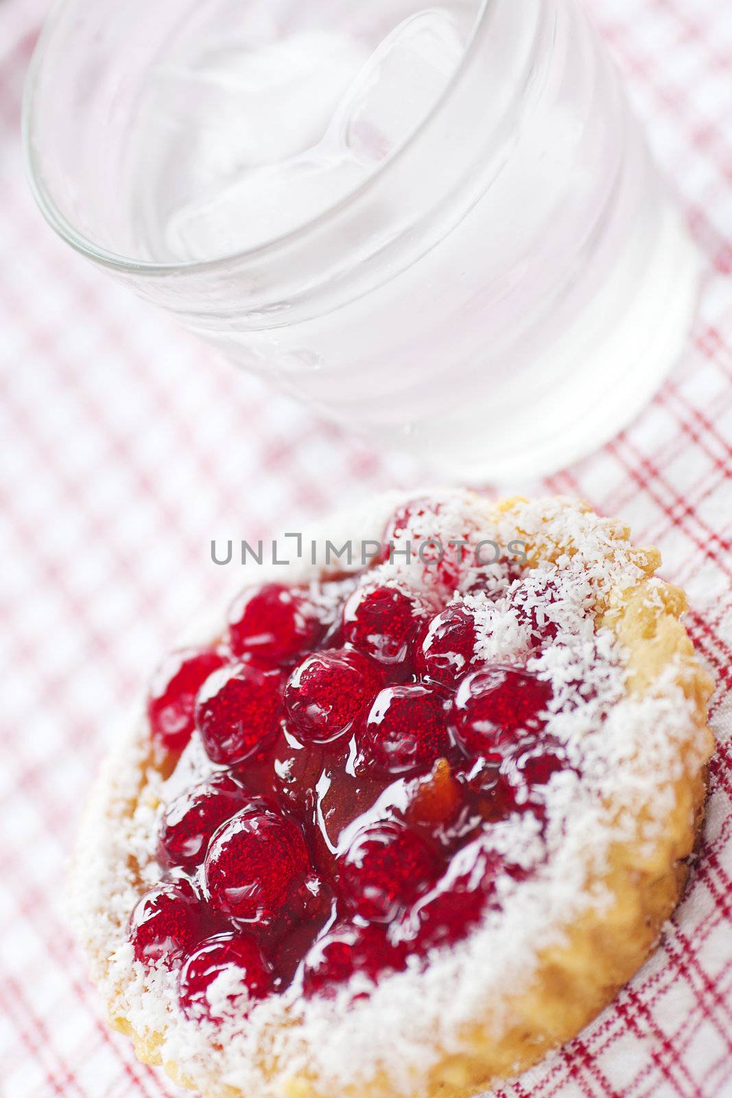 beautiful cake with berries and water on plaid fabric