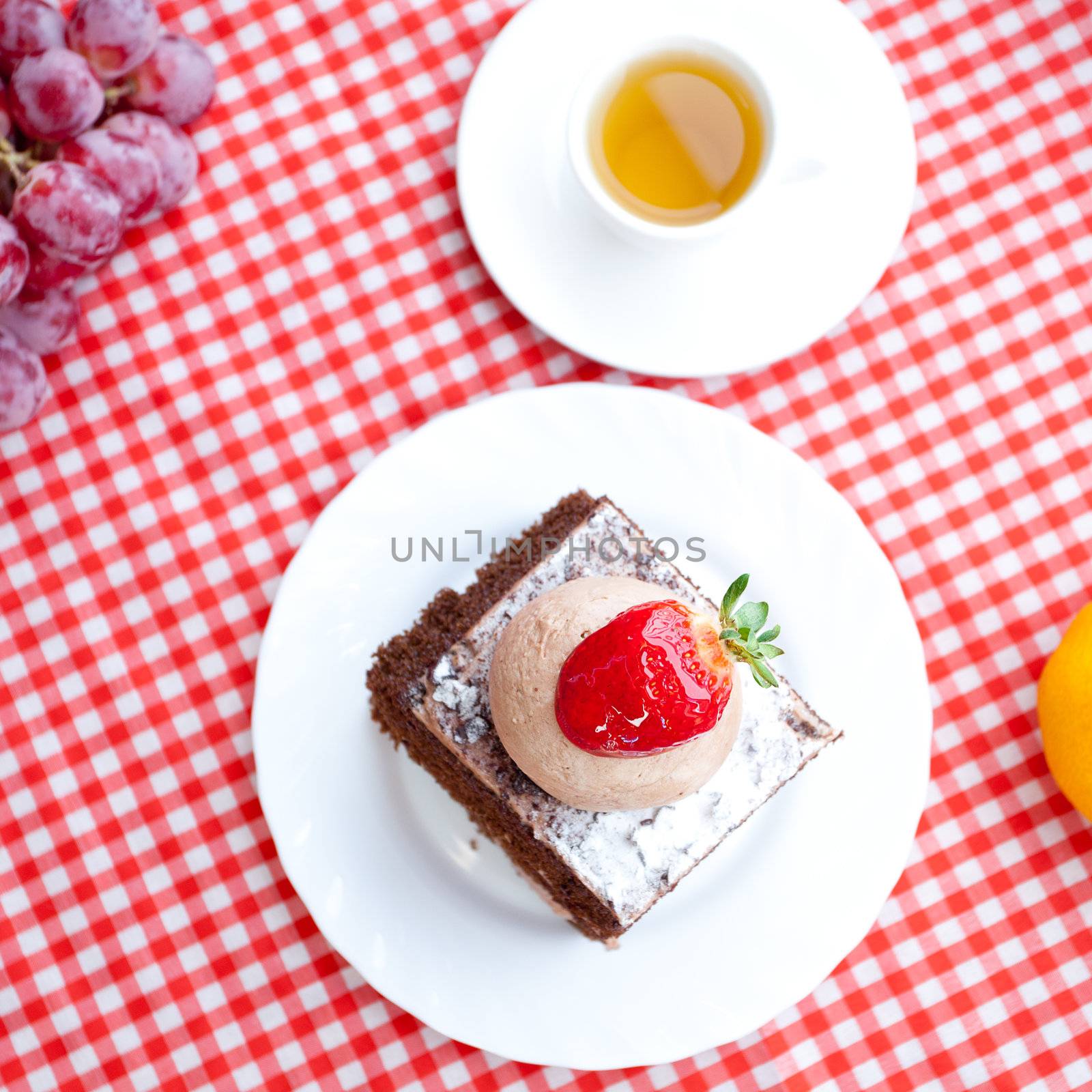 beautiful cake with strawberry,tangerine,grape and tea on plaid fabric