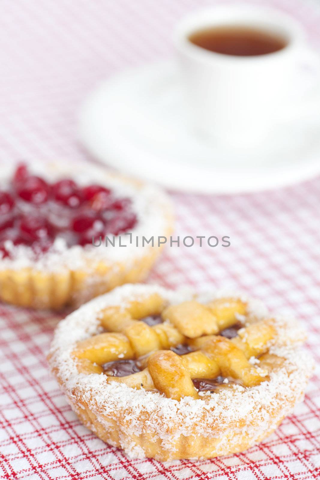 beautiful cake with berries and tea on plaid fabric by jannyjus