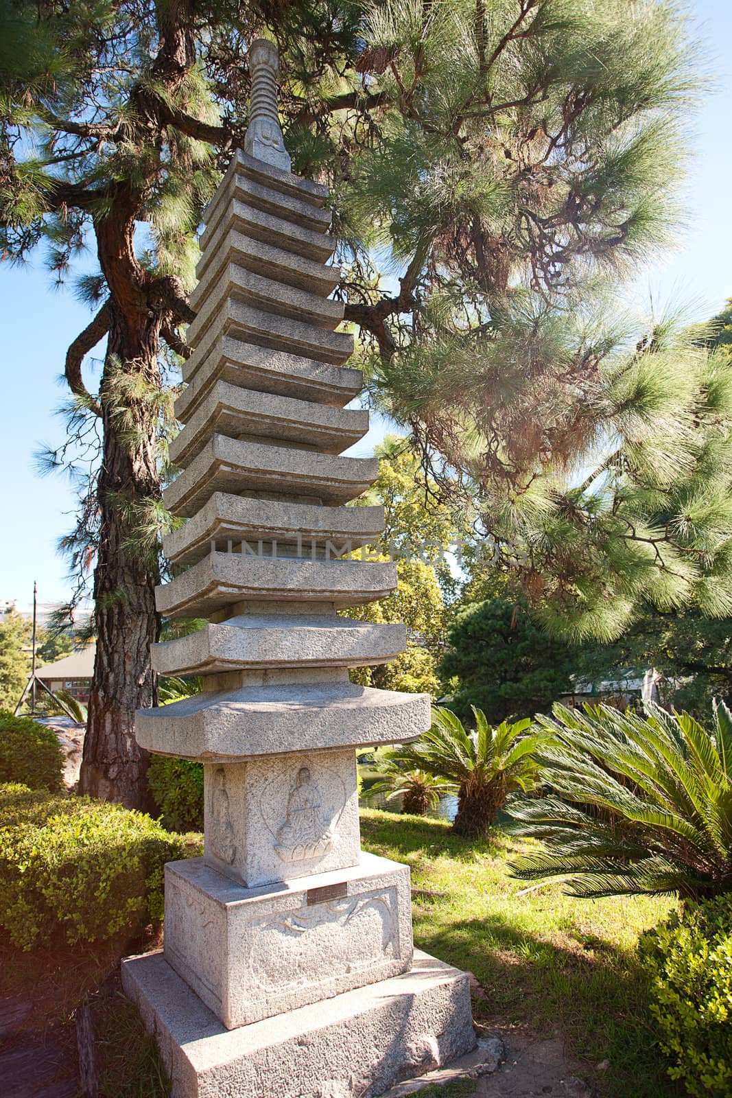 stone pagoda on the background of green trees by jannyjus