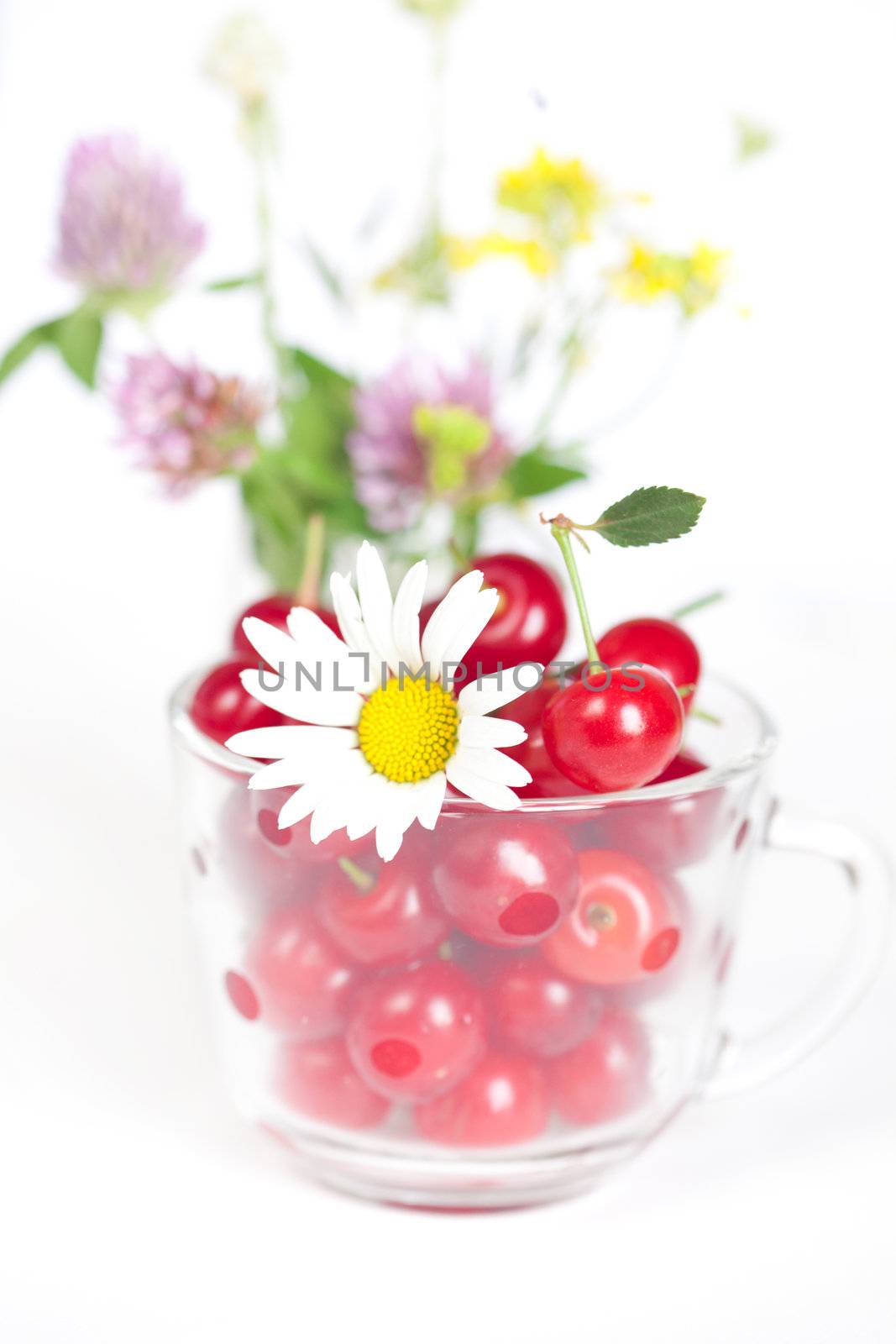 glass cup with cherries and a bouquet of wildflowers