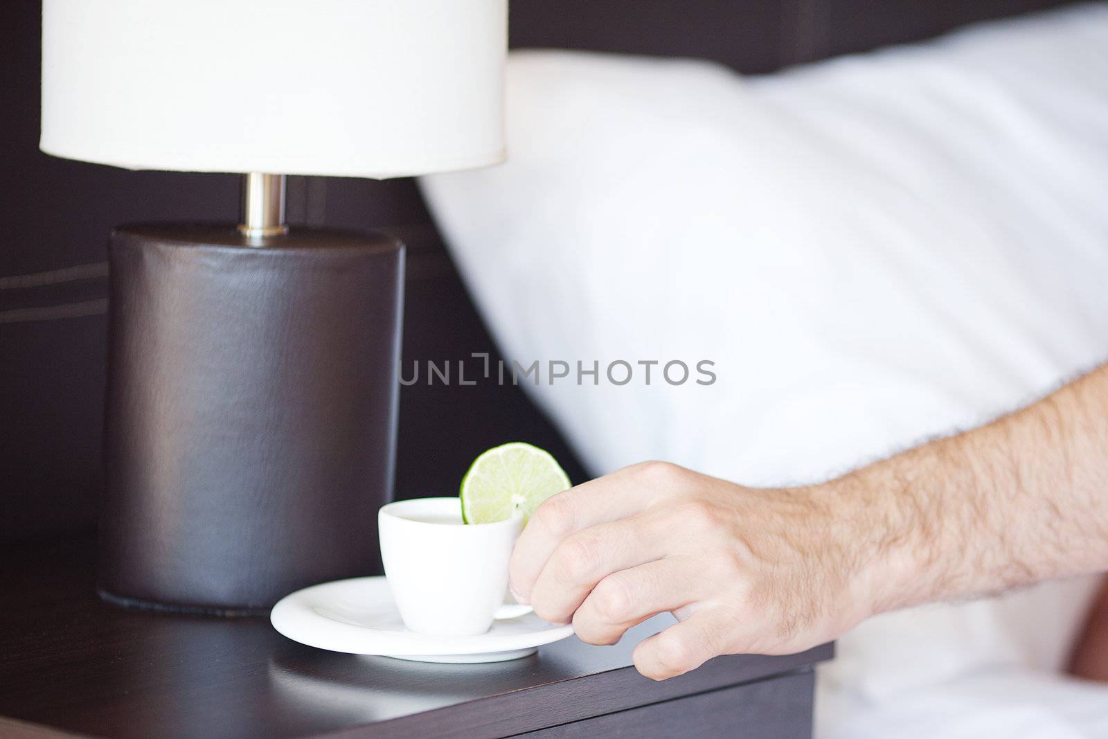 man hand, a cup of tea on the bedside table and lamp by jannyjus