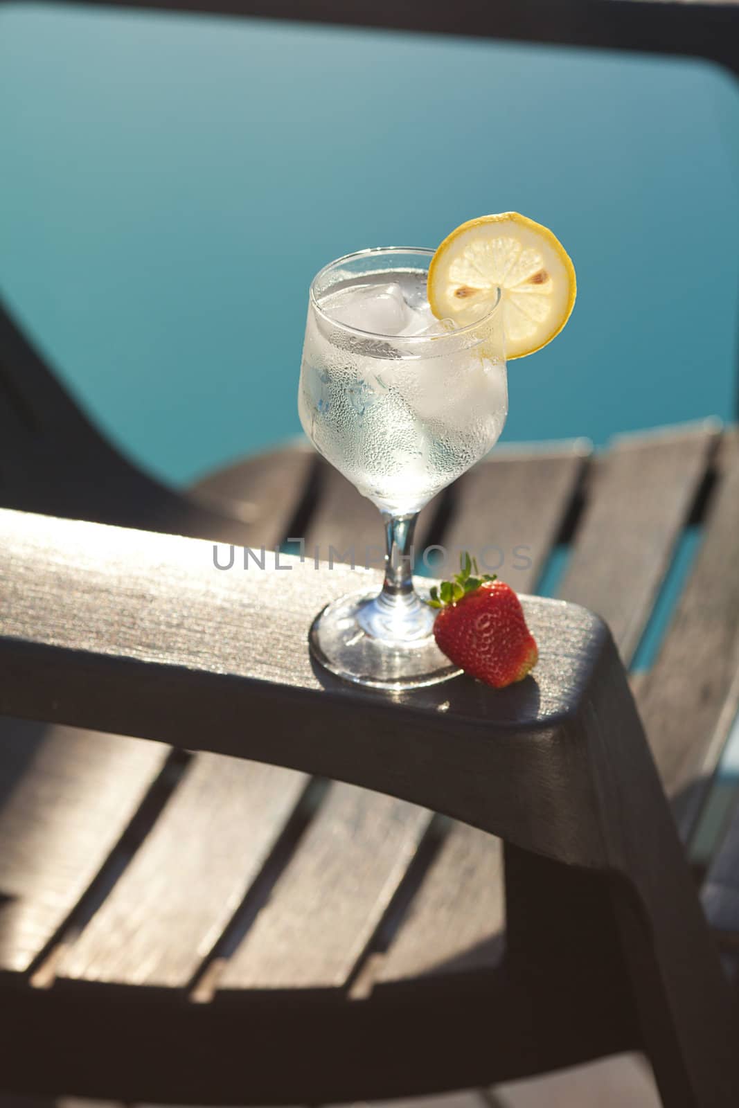 Swimming pool, lounge, a wine glass with ice, lemon and strawberry