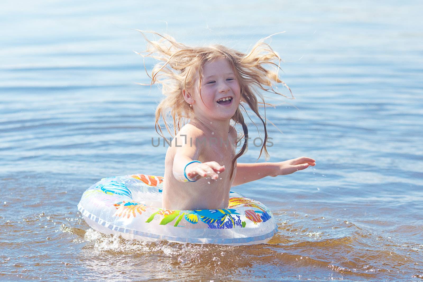 beautiful little girl splashes in the water