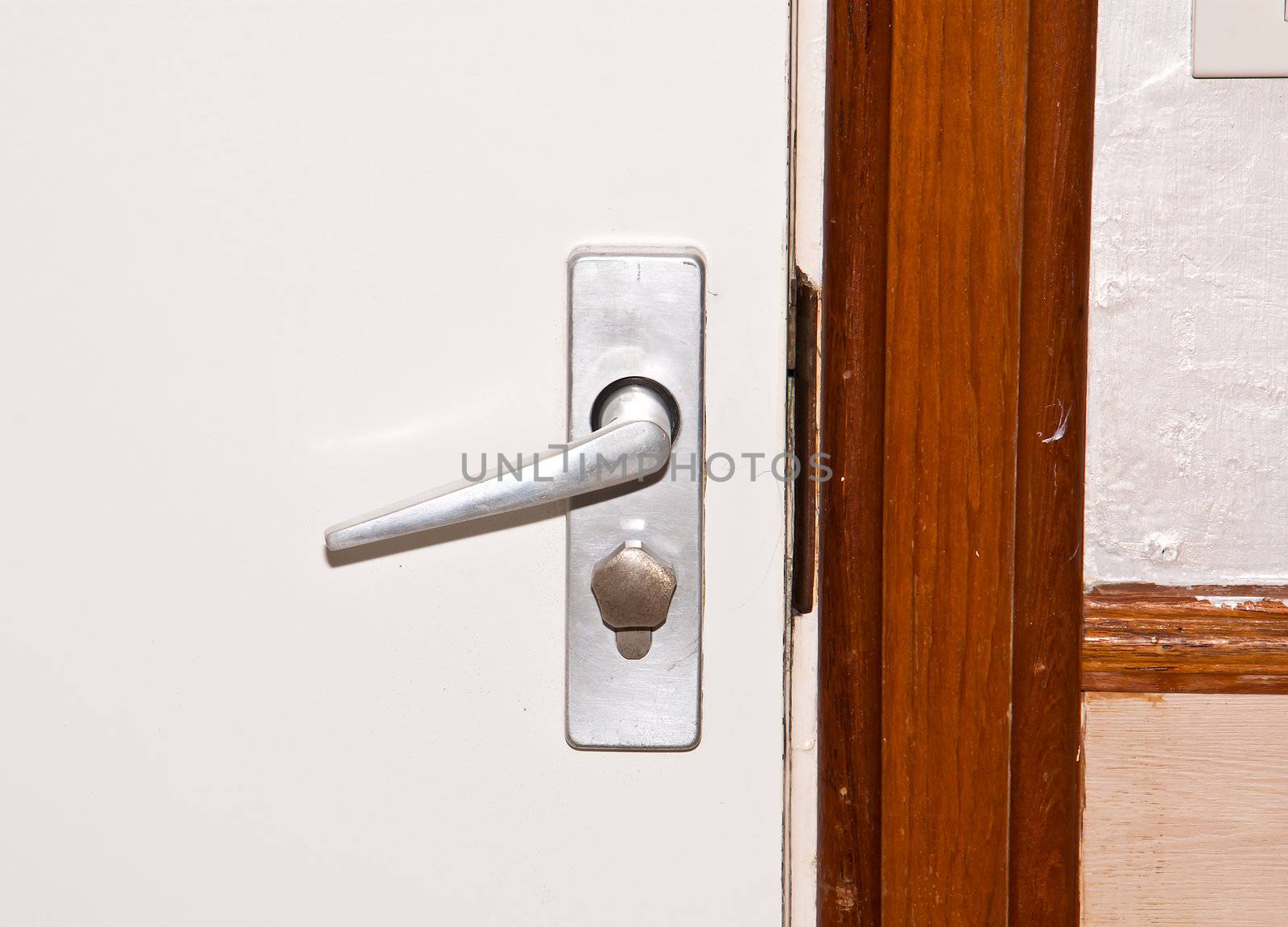 Aluminium door knob on the white door