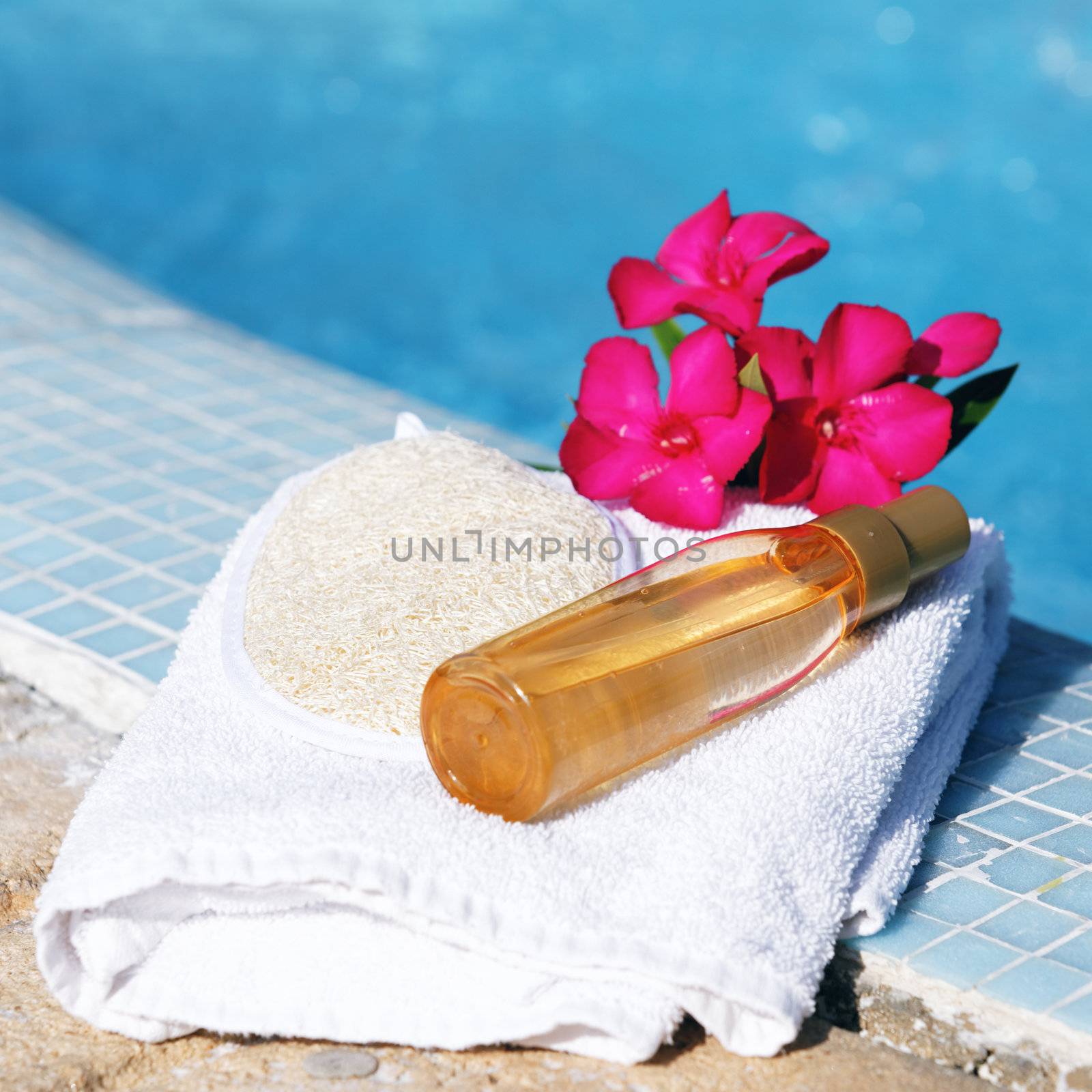 massage oil on white towel beside a pool 