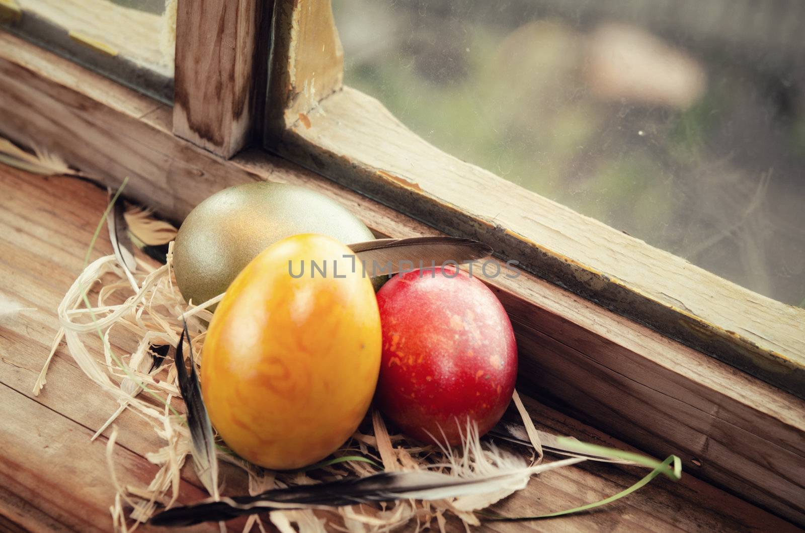 Colored Eggs are laid on feathers on a window sill