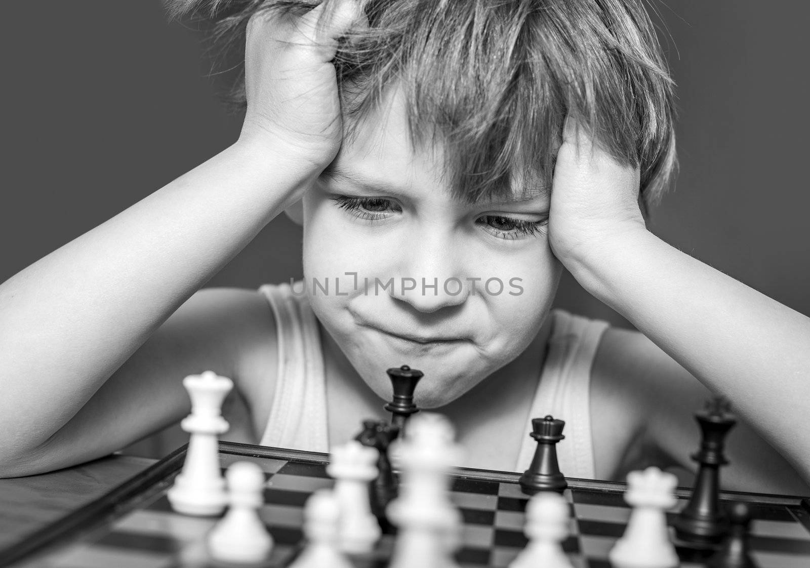 Boy playing chess, thinking how to make a move.