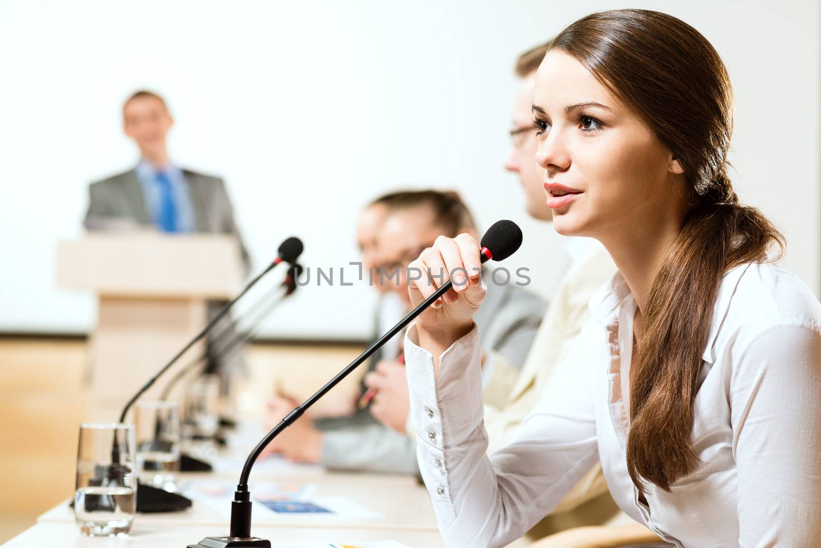 Business woman speaks into a microphone by adam121