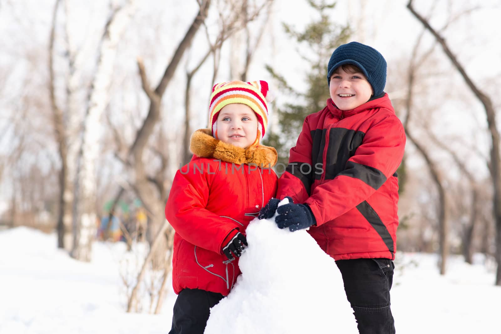 Boy and girl playing with snow in winter park, spending time together outdoors