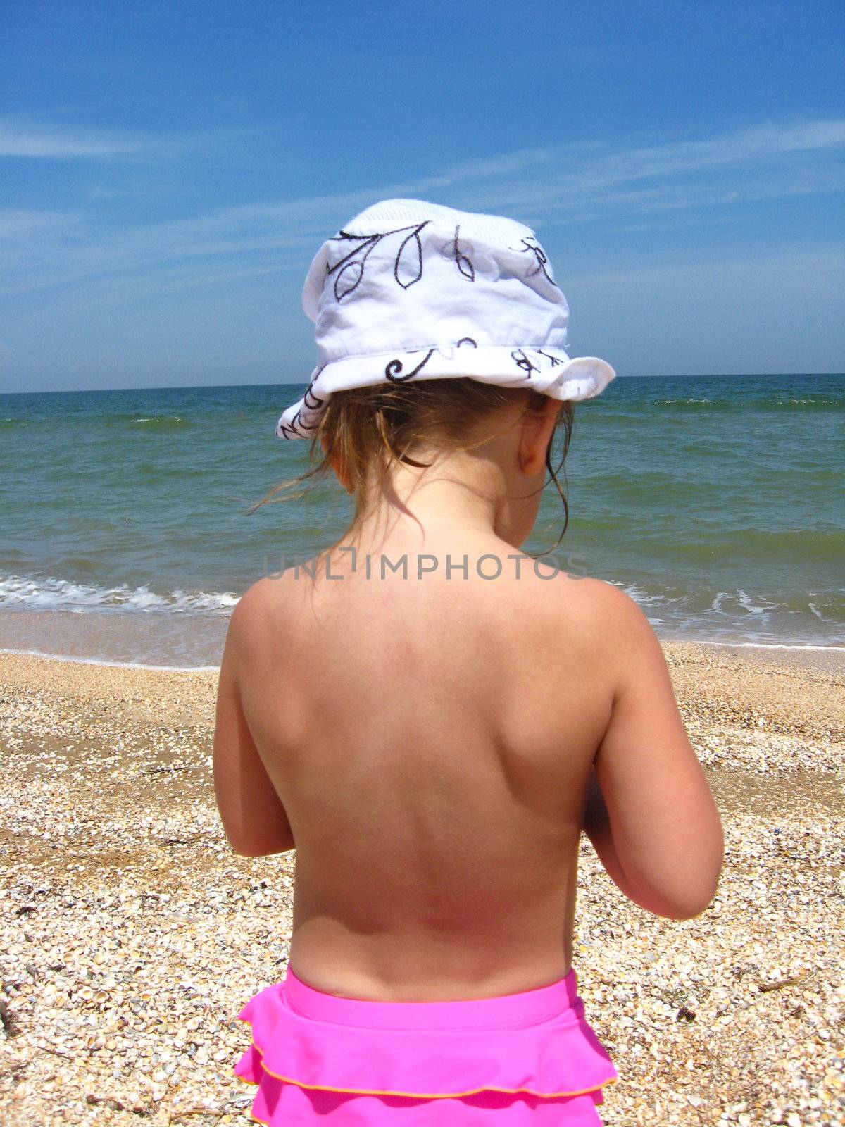 The back of little girl standing near the sea