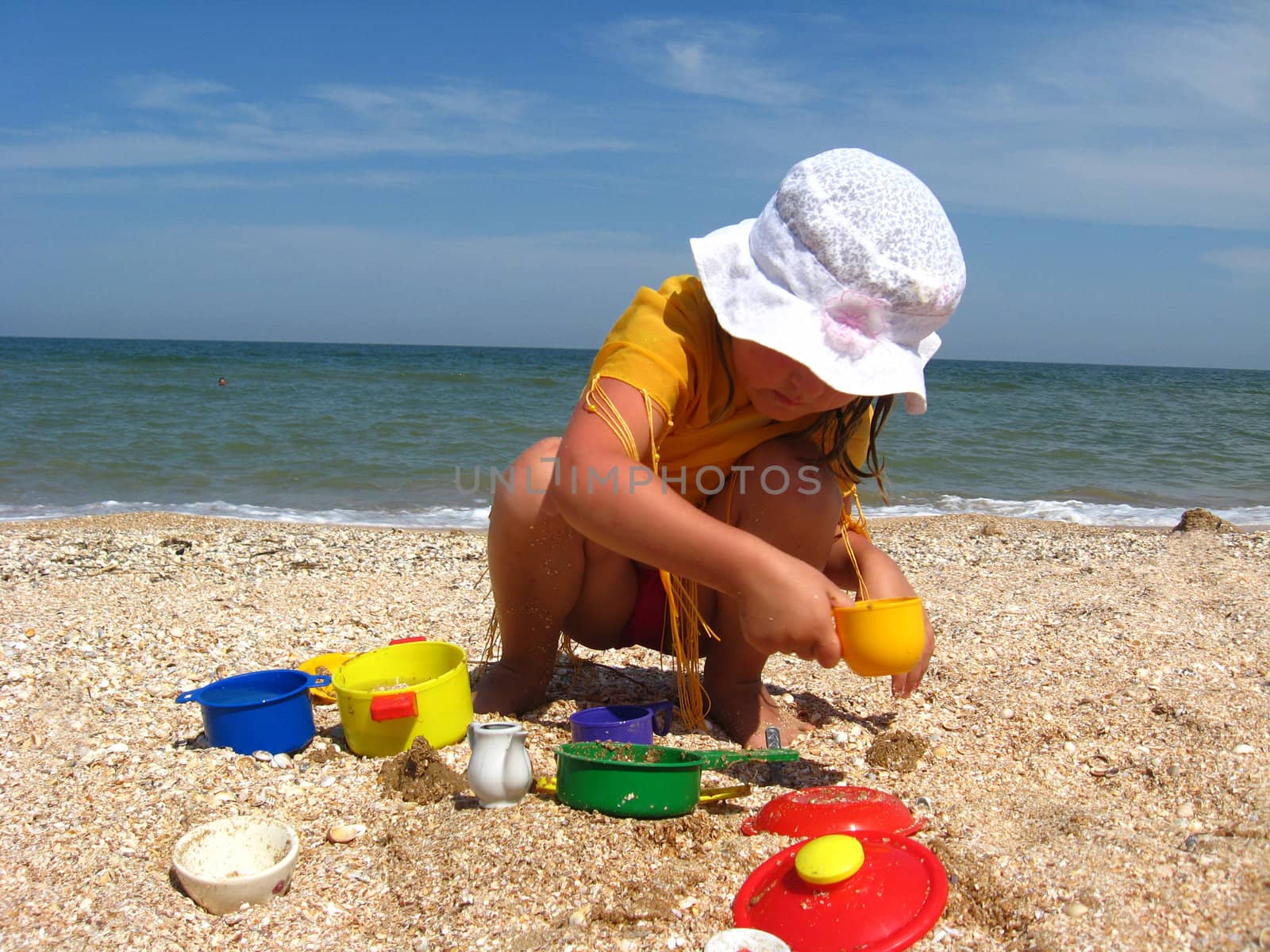 little girl plays on the sand at the sea