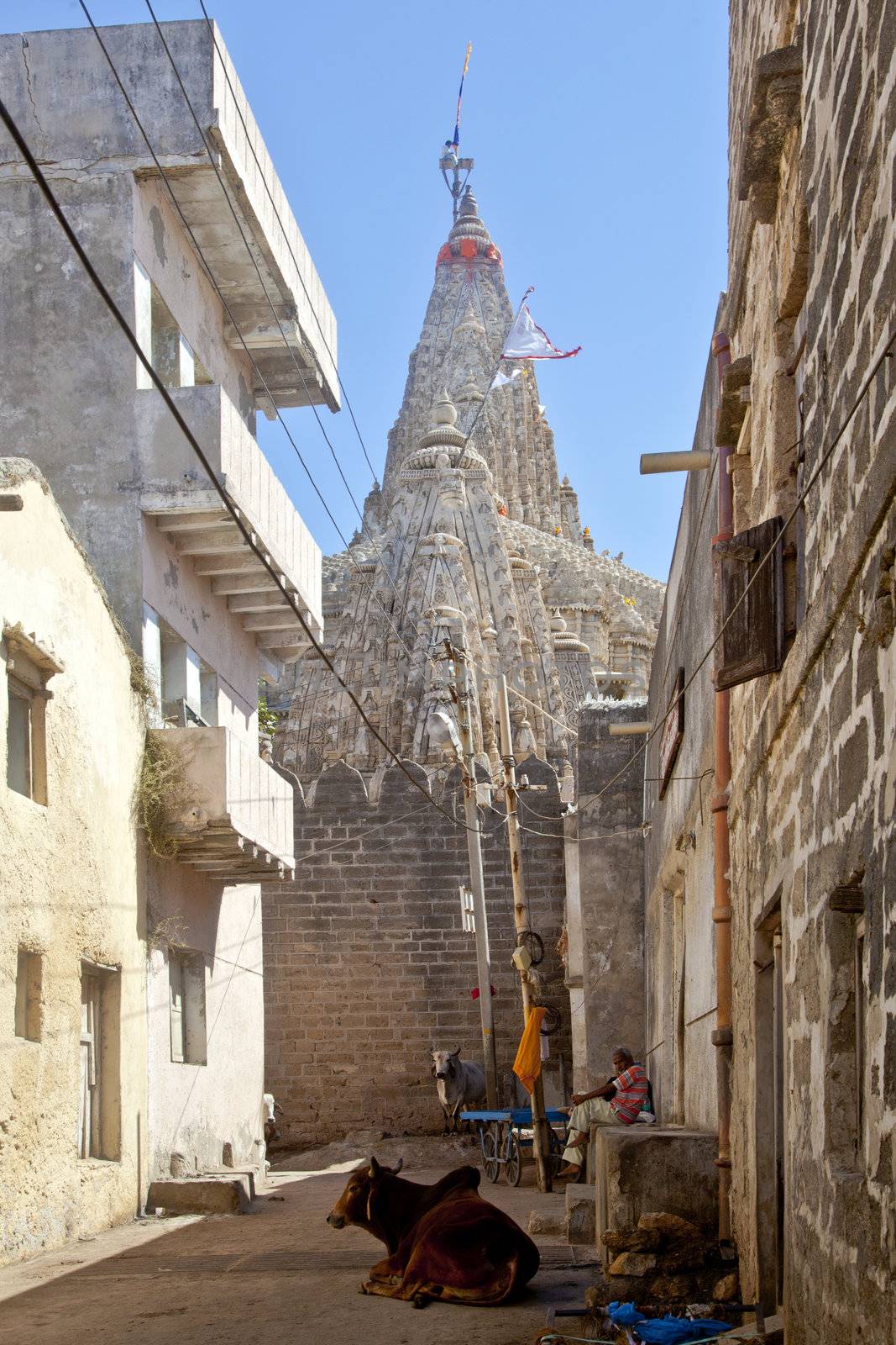Vertical capture from one of the alleys around Shree Dwarakadheesh Krishna Temple in Dwarka showing a man climbing the steeple to change the colors of the flag. This is done frequently throughout the day