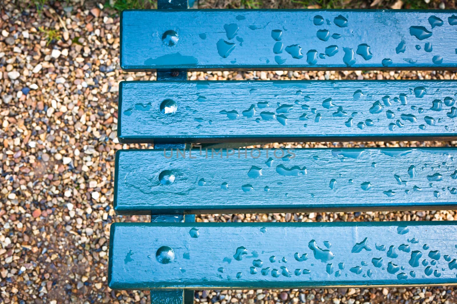 Rain drops on a blue park bench