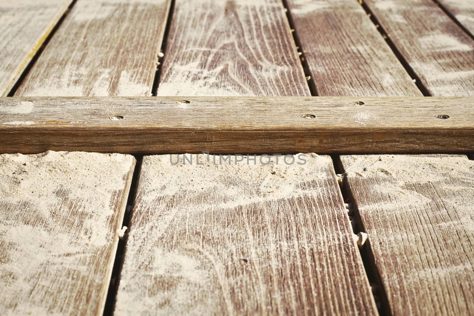 Close up of a wooden surface with sand on it
