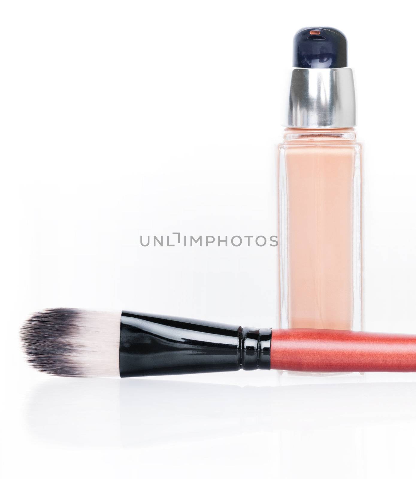 Cosmetic liquid foundation and brush on white background