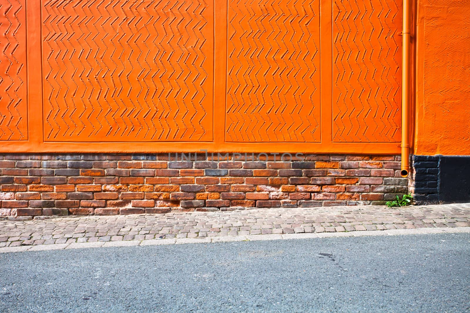 Bright orange wall with a sloping pavement as a background