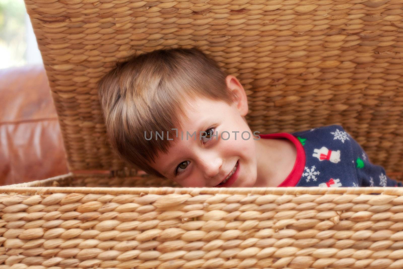 A young child playing hide and seek in a wicker container