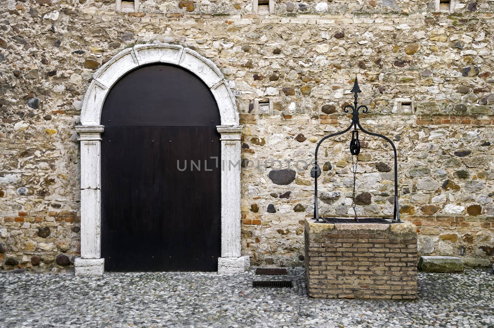 Stronghold front door on a stone wall with stony well